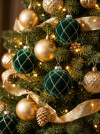 Fragment żywej choinki bogato przystrojonej w eleganckiej tonacji. Wyrazistym akcentem są ciemnozielone, welurowe bombki ze złotą kratką z brokatu, które zawieszono naprzemiennie z gładkimi oraz tłoczonymi bombkami w kolorze złota. Kompozycję przeplata złota, szeroka wstążka, a całość rozświetlają drobne, ciepłe lampki