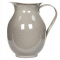 Zdjęcie produktowe na gładkim, białym tle (packshot). Prezentuje szary dzbanek emaliowany z wygodnym uchem i wyprofilowanym dzióbkiem. Błyszcząca powierzchnia odbija oświetlenie studyjne, a kolor przypomina jasną szarość o strukturze drobnego melanżu (często spotykaną w tradycyjnych naczyniach emaliowanych