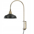 Zdjęcie produktowe na białym tle (packshot). Lampa ścienna w stylu loft/industrialnym. Składa się z długiego, łukowato wygiętego ramienia w kolorze patynowanego mosiądzu oraz czarnego, półokrągłego, metalowego klosza. Konstrukcja pozwala na montaż bezpośrednio do ściany za pomocą płaskiej bazy, z której wychodzi czarny przewód zasilający.
