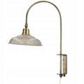 Zdjęcie produktowe na gładkim, białym tle (packshot). Klasyczna lampa ścienna (kinkiet) w stylu vintage lub loft. Składa się z szarego, metalowego klosza o lekko spłaszczonym kształcie oraz długiego, wygiętego w łuk cienkiego ramienia w kolorze antycznego mosiądzu. Ramię osadzone jest w prostokątnym uchwycie ściennym wyposażonym w mechanizm umożliwiający regulację wysokości, od którego odchodzi dół biały przewód zasilający.