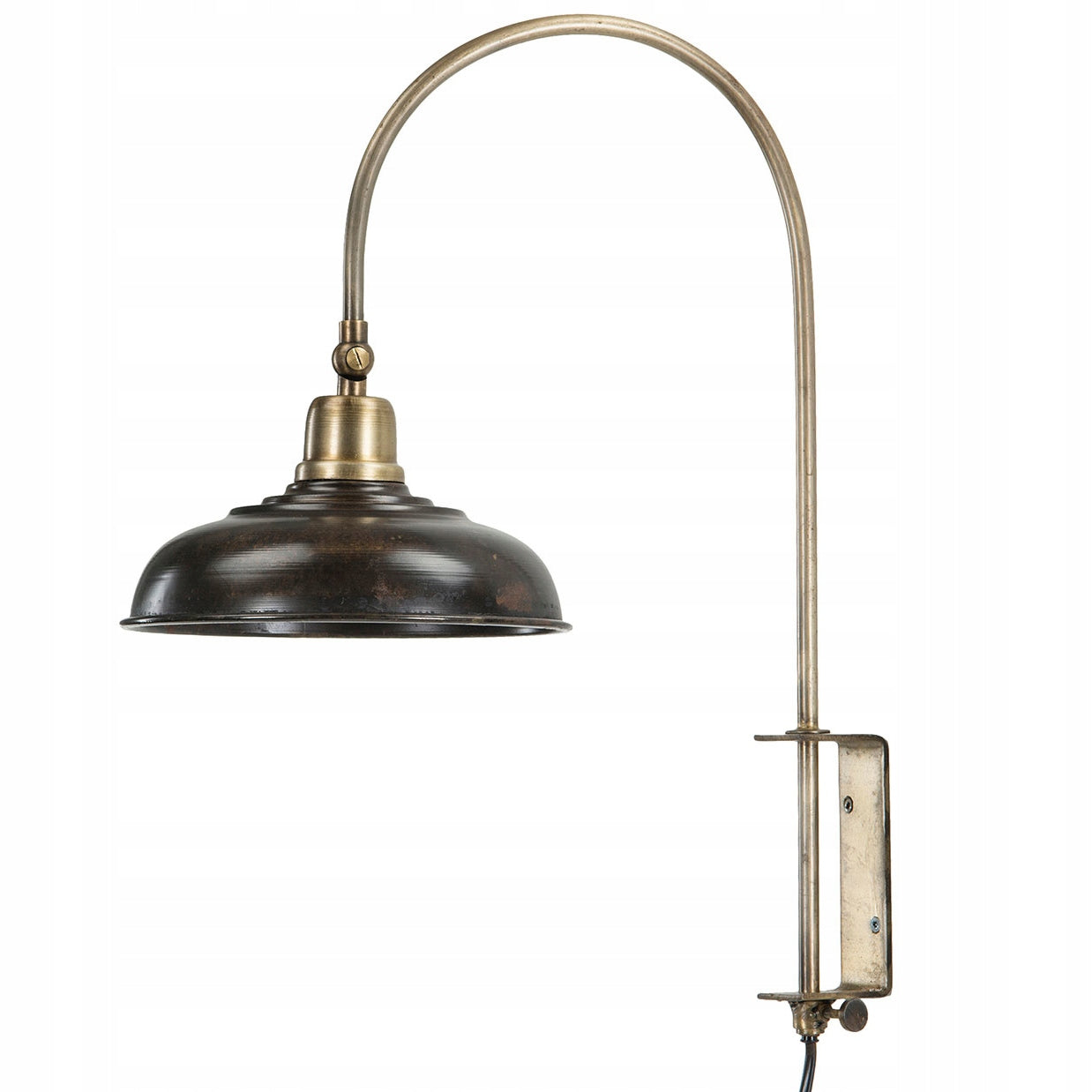 Zdjęcie produktowe na białym tle (packshot). Lampa ścienna (kinkiet) o surowym, industrialnym designie. Posiada ciemnobrązowy (rdzawy), metalowy klosz o spłaszczonym kształcie z elementami w kolorze antycznego mosiądzu. Ramię lampy jest długie, wygięte w łuk i osadzone w masywnym, prostokątnym uchwycie ściennym, umożliwiającym regulację jej wysokości za pomocą pokrętła.