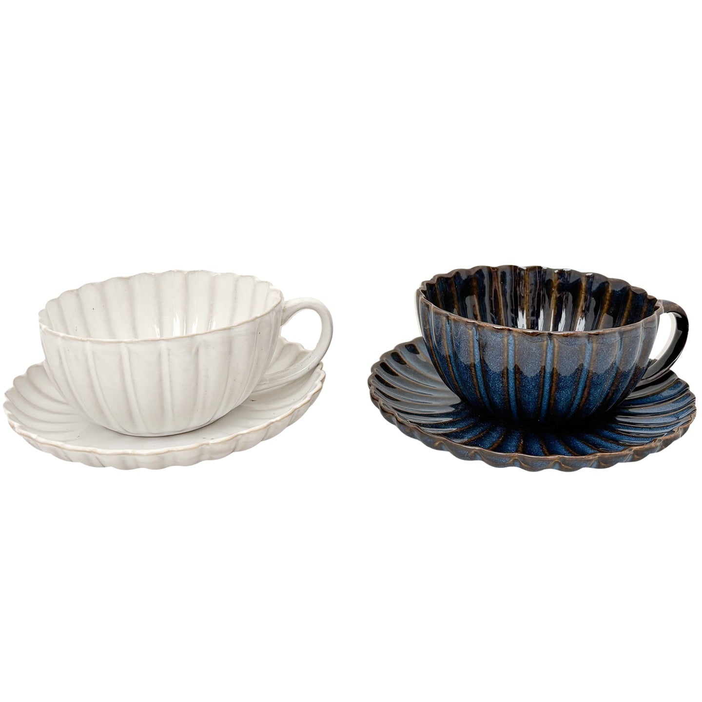Zdjęcie produktowe typu packshot wykonane na jednolitym, białym tle. Przedstawia zestaw dwóch ceramicznych filiżanek z dopasowanymi spodkami. Naczynia charakteryzują się elegancką, prążkowaną fakturą oraz nieregularnymi, pofalowanymi brzegami przypominającymi płatki kwiatów. Lewa filiżanka jest w kolorze złamanej bieli, natomiast prawa pokryta jest lśniącym, głębokim, granatowym szkliwem z brązowymi akcentami na rantach.