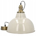 Zdjęcie produktowe na białym, gładkim tle (packshot). Wisząca lampa w stylu industrialnym lub vintage. Posiada duży, kopułowy klosz pokryty błyszczącą emalią w odcieniu złamanej bieli (kremowym/jasnoszarym). Górna część klosza jest schodkowa i płynnie przechodzi w dekoracyjny, mosiężny element z wycięciami wentylacyjnymi. Od lampy odchodzi czarny przewód zasilający, zakończony okrągłą, szczotkowaną podsufitką w kolorze mosiądzu.