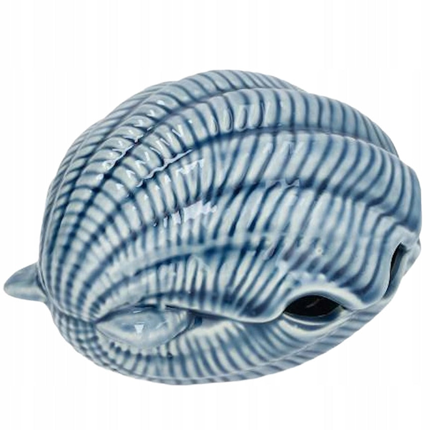 Ceramiczna ozdoba w kształcie pękatej muszli. Przedmiot pokryty jest błyszczącym, niebieskim szkliwem z wyraźnie zaznaczonymi, wypukłymi prążkami. Kształt z małym, bocznym otworem sugeruje funkcję lampionu na tealight lub oryginalnej figurki dekoracyjnej. Zdjęcie produktowe typu packshot wykonane na jednolitym, białym tle.