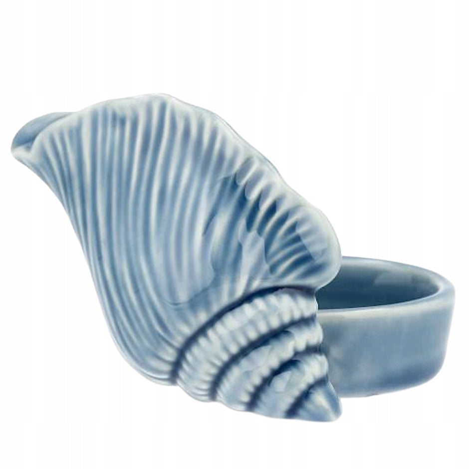 Ceramiczny świecznik zaprojektowany w kształcie dużej muszli. Posiada wyraźną, ryflowaną strukturę oraz błyszczące wykończenie w odcieniach morskiego błękitu. Z tyłu muszli znajduje się specjalnie wyprofilowane, okrągłe miejsce na świeczkę typu tealight. Zdjęcie produktowe typu packshot wykonane na jednolitym, białym tle.