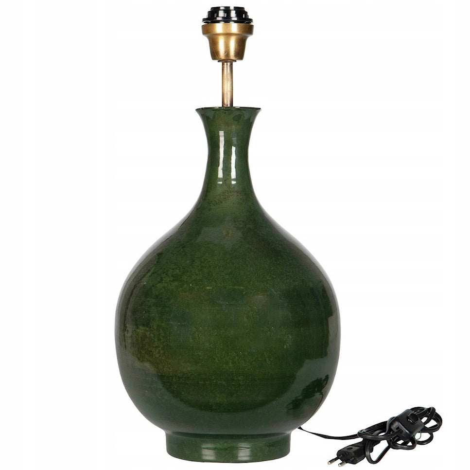 Ceramiczna podstawa lampy stołowej o eleganckim kształcie pękatej butli. Powierzchnia wykończona jest ciemnozielonym, lśniącym szkliwem z subtelnym cieniowaniem. Na górze zamontowana jest mosiężna oprawka z gwintem na żarówkę, a u dołu po prawej stronie widoczny jest czarny przewód zasilający z włącznikiem ręcznym i wtyczką. Zdjęcie produktowe typu packshot wykonane na jednolitym, białym tle.