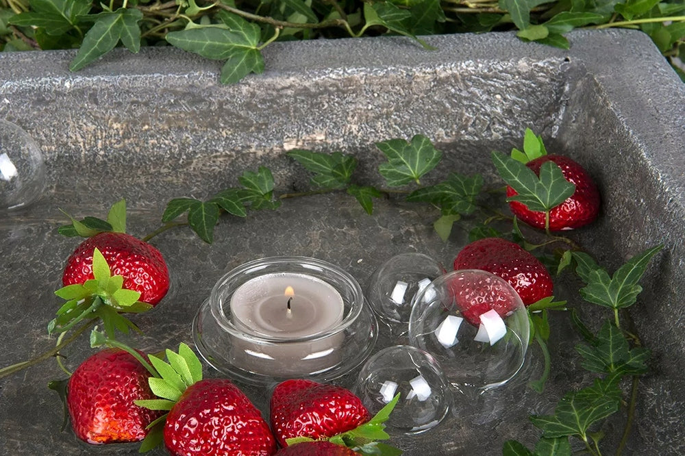 Nastrojowa dekoracja wodna zaaranżowana w kwadratowej, kamiennej misie (przypominającej poidło dla ptaków). Na powierzchni wody unoszą się sztuczne truskawki, przezroczyste szklane kule, gałązki zielonego bluszczu oraz mały, szklany świecznik z zapalonym tealightem. Połączenie wody, światła i czerwonych akcentów tworzy relaksującą i bardzo oryginalną kompozycję.